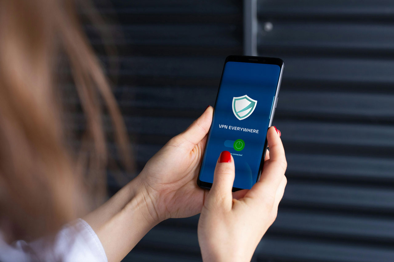 Close-up of a womans hands using a VPN app on a smartphone, emphasizing digital security.